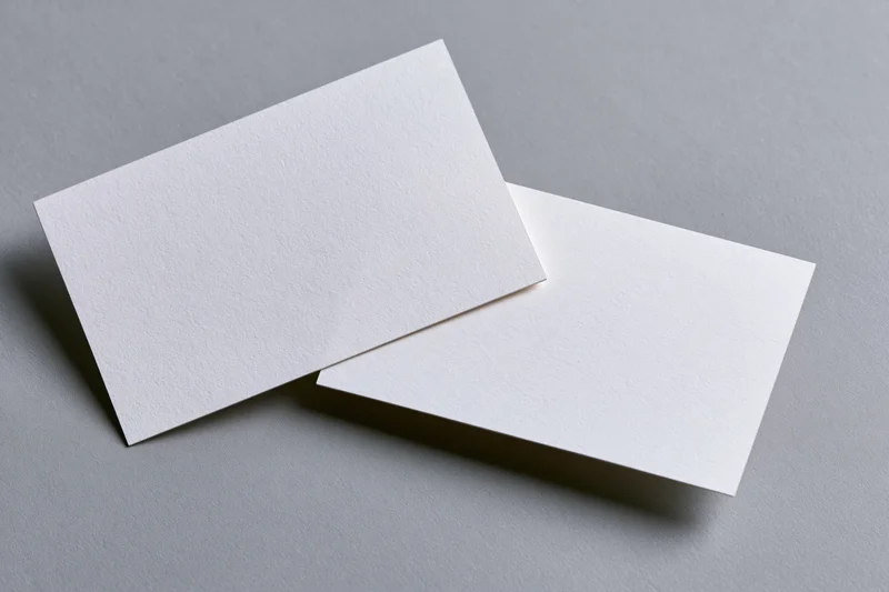 Two blank white business cards arranged at slight angles on a gray surface