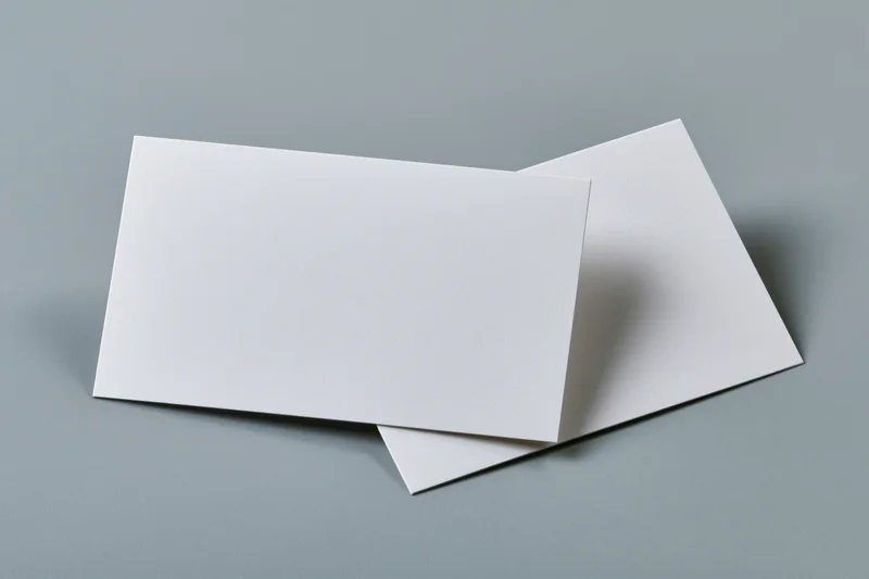 Two blank white business cards arranged at slight angles on a gray surface