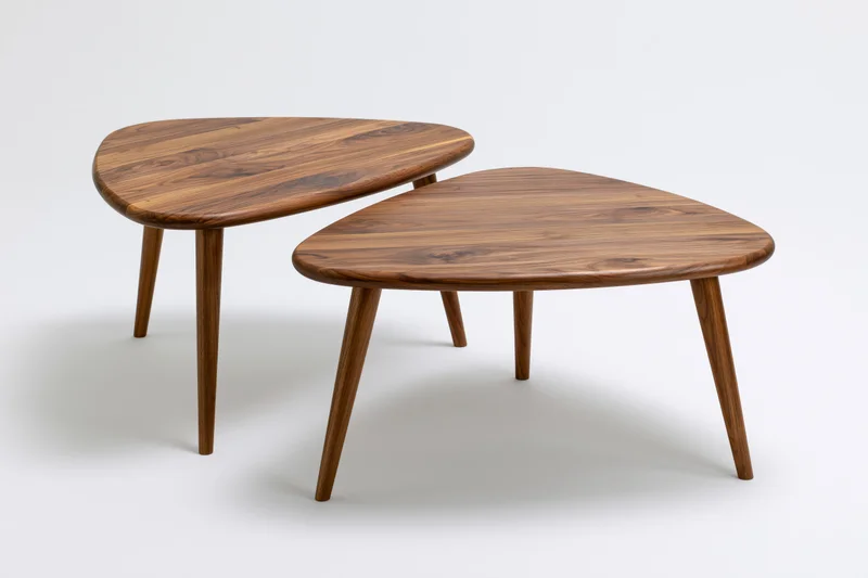 Two mid-century modern wooden nesting coffee tables with triangular tops and tapered legs on white background