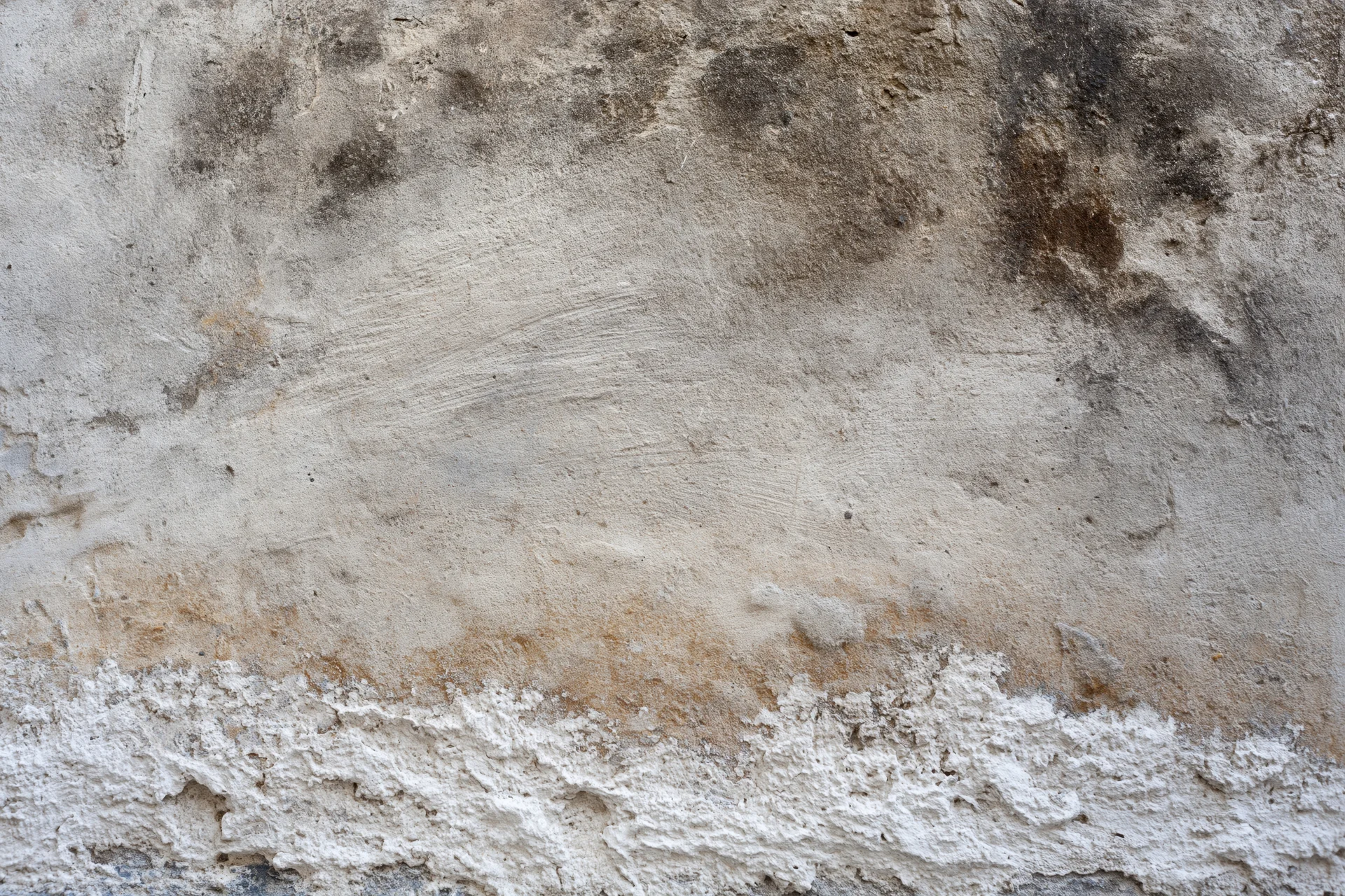 Weathered concrete wall surface with cracks and discoloration filling the frame