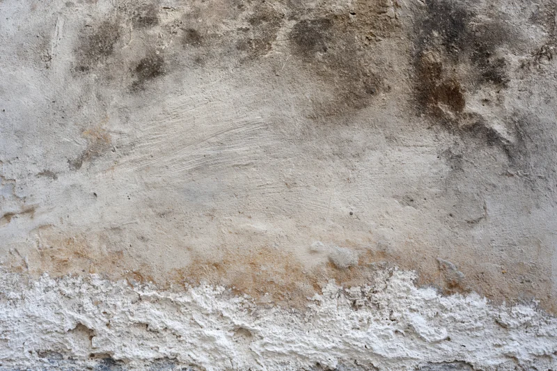 Weathered concrete wall surface with cracks and discoloration filling the frame