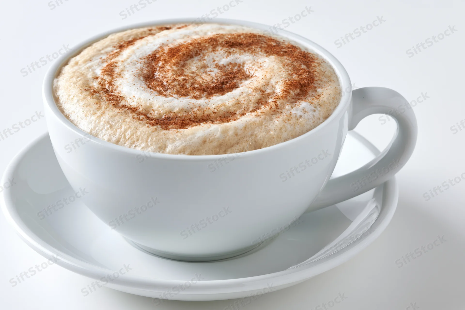 White ceramic cappuccino cup with cinnamon swirl foam on matching saucer against plain white background