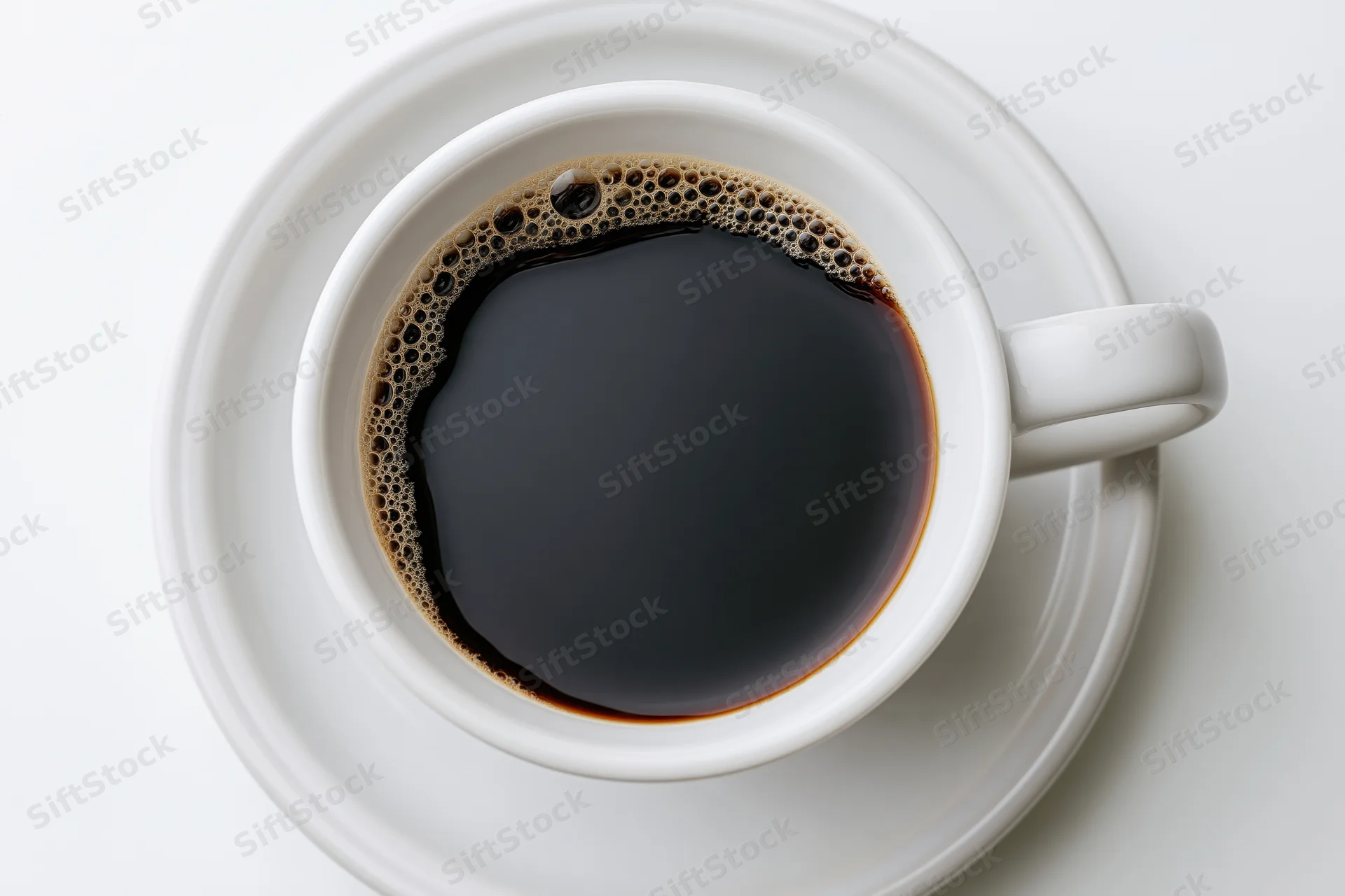 White ceramic coffee cup filled with black coffee and foam viewed from above on a plain white surface