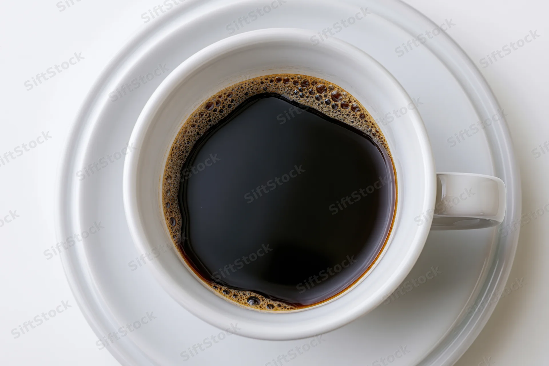 Overhead view of a white ceramic coffee cup filled with black coffee on a saucer