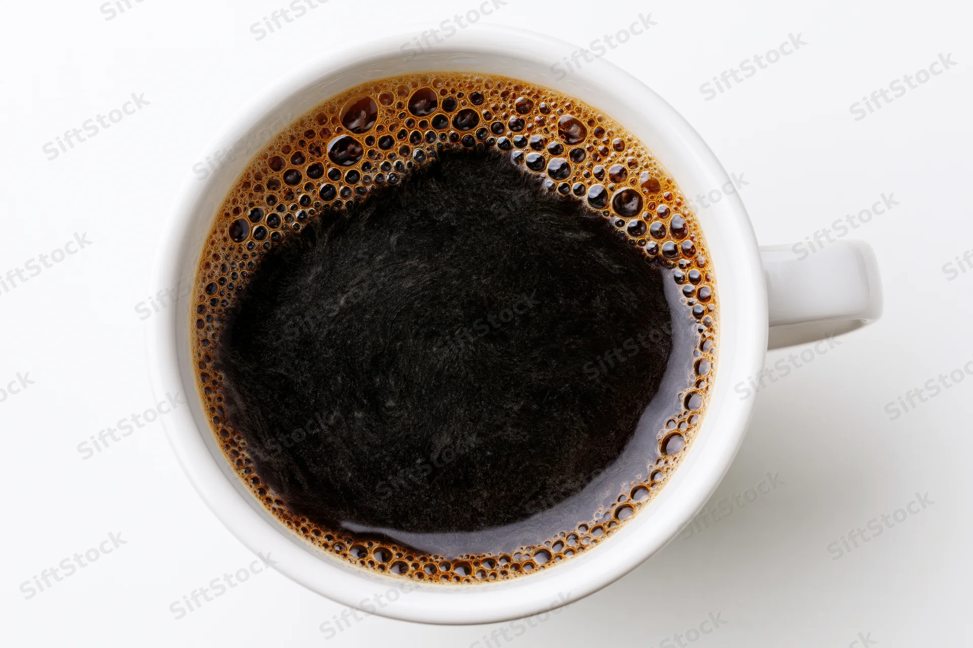 Overhead view of a white ceramic mug filled with black coffee and foam on a plain white surface