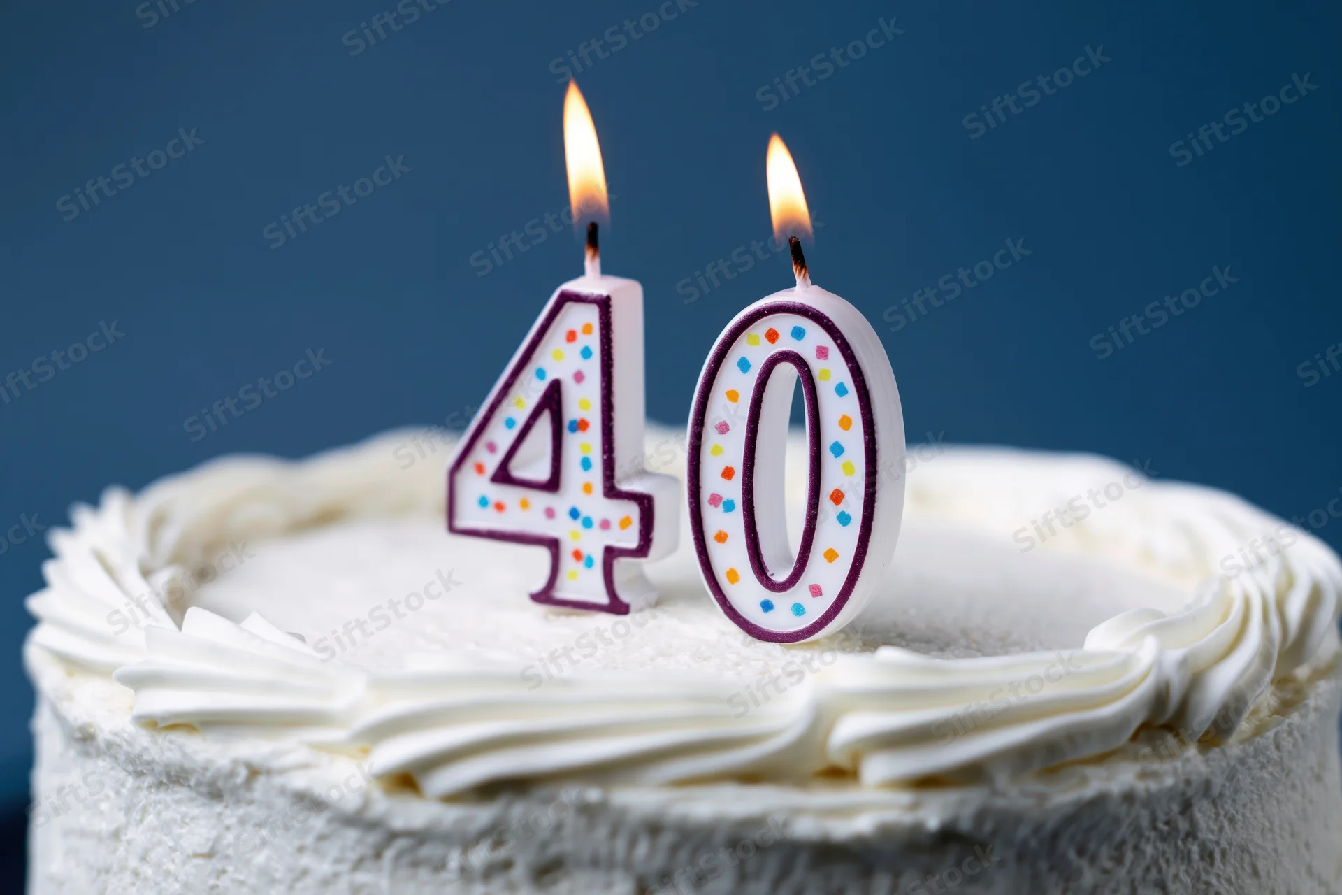 White frosted cake with lit number 40 candles for birthday celebration