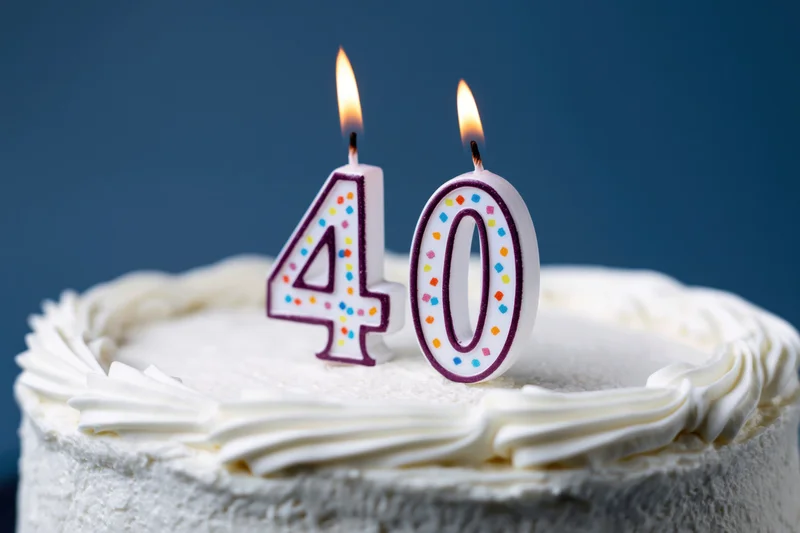 White frosted cake with lit number 40 candles for birthday celebration
