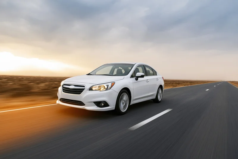 White sedan driving fast on rural asphalt road at sunset