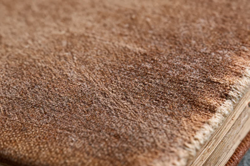Closeup of worn antique book cover showing aged leather texture and frayed edge