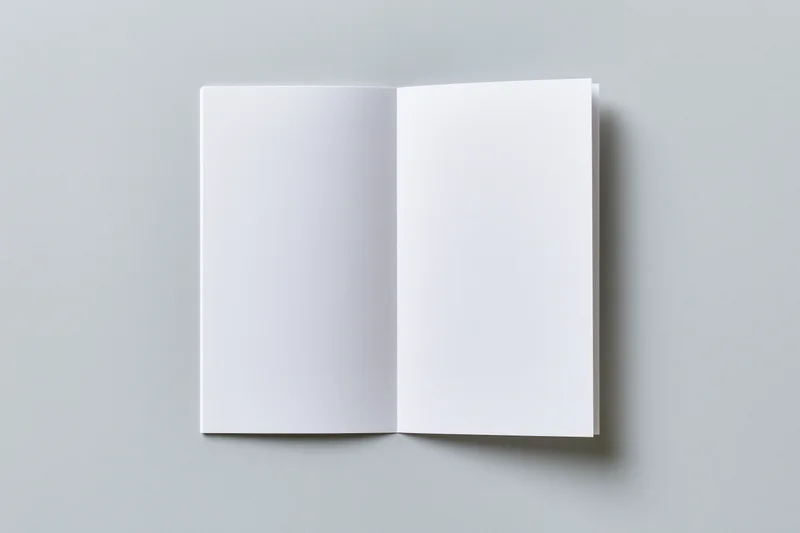 Open blank white brochure lying flat on gray surface with copyspace