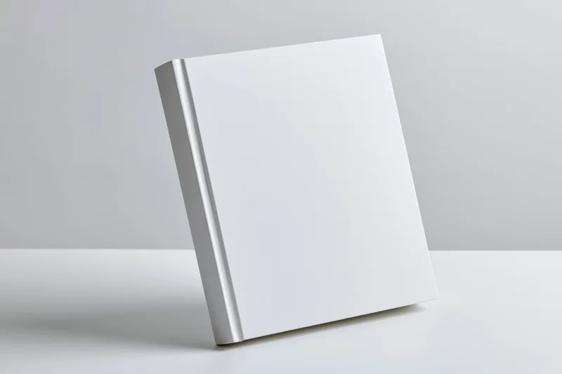 Blank white hardcover book leaning against a white surface with copyspace
