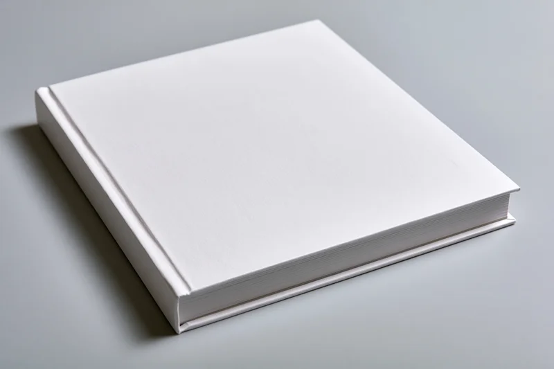 Blank white hardcover book lying flat on gray surface