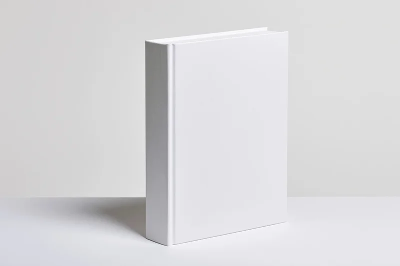 Blank white hardcover book standing upright on a white surface