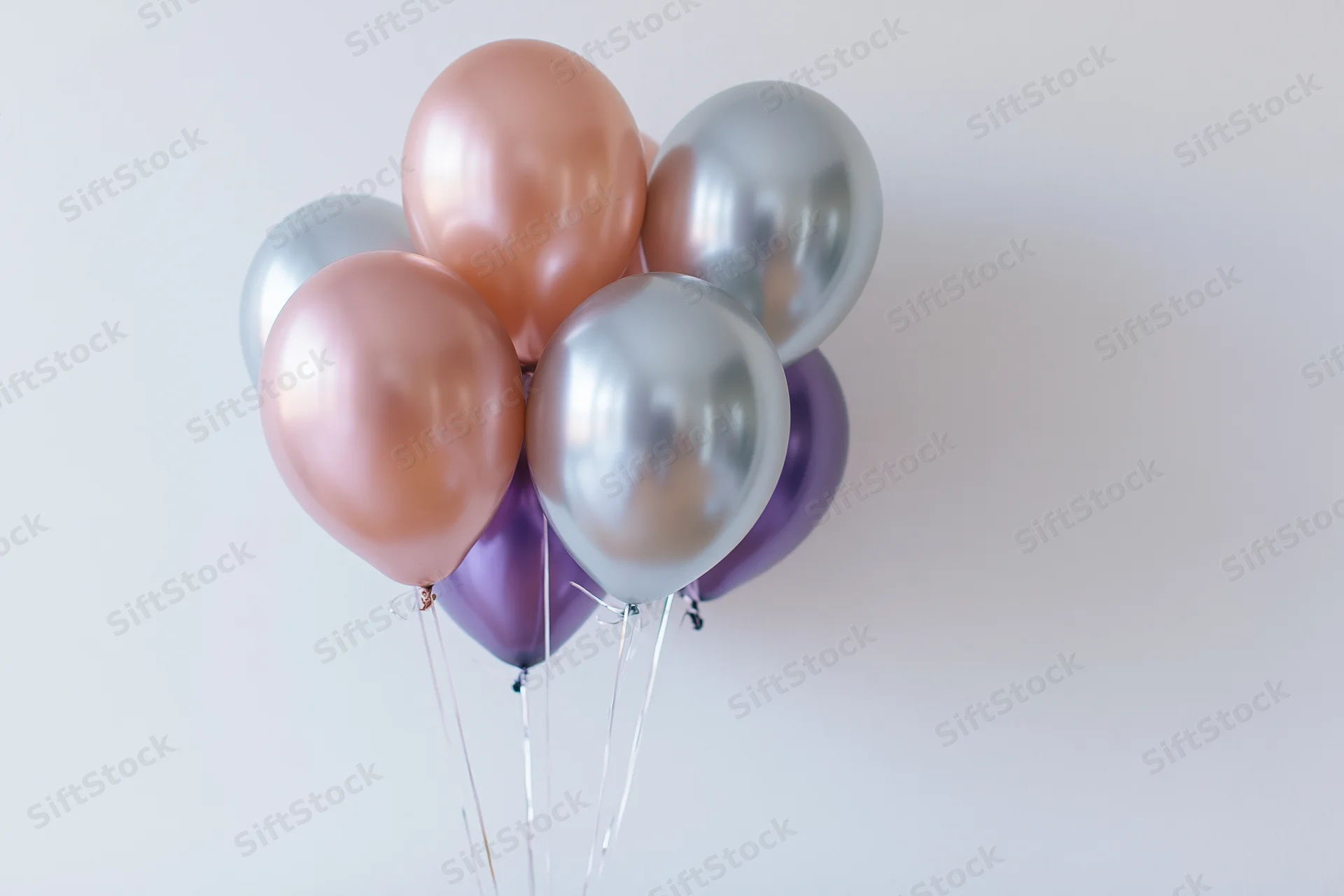 Metallic helium balloons clustered together against a white background with copyspace