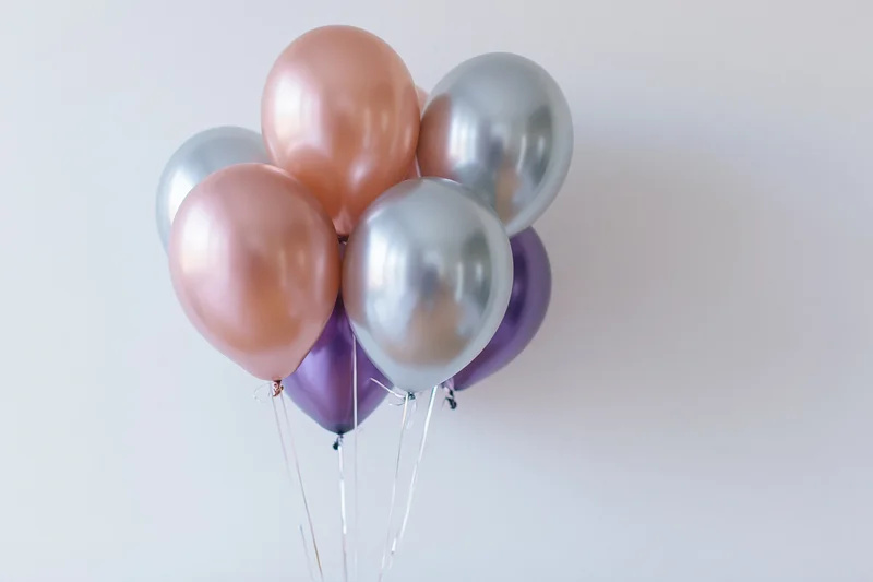 Metallic helium balloons clustered together against a white background with copyspace