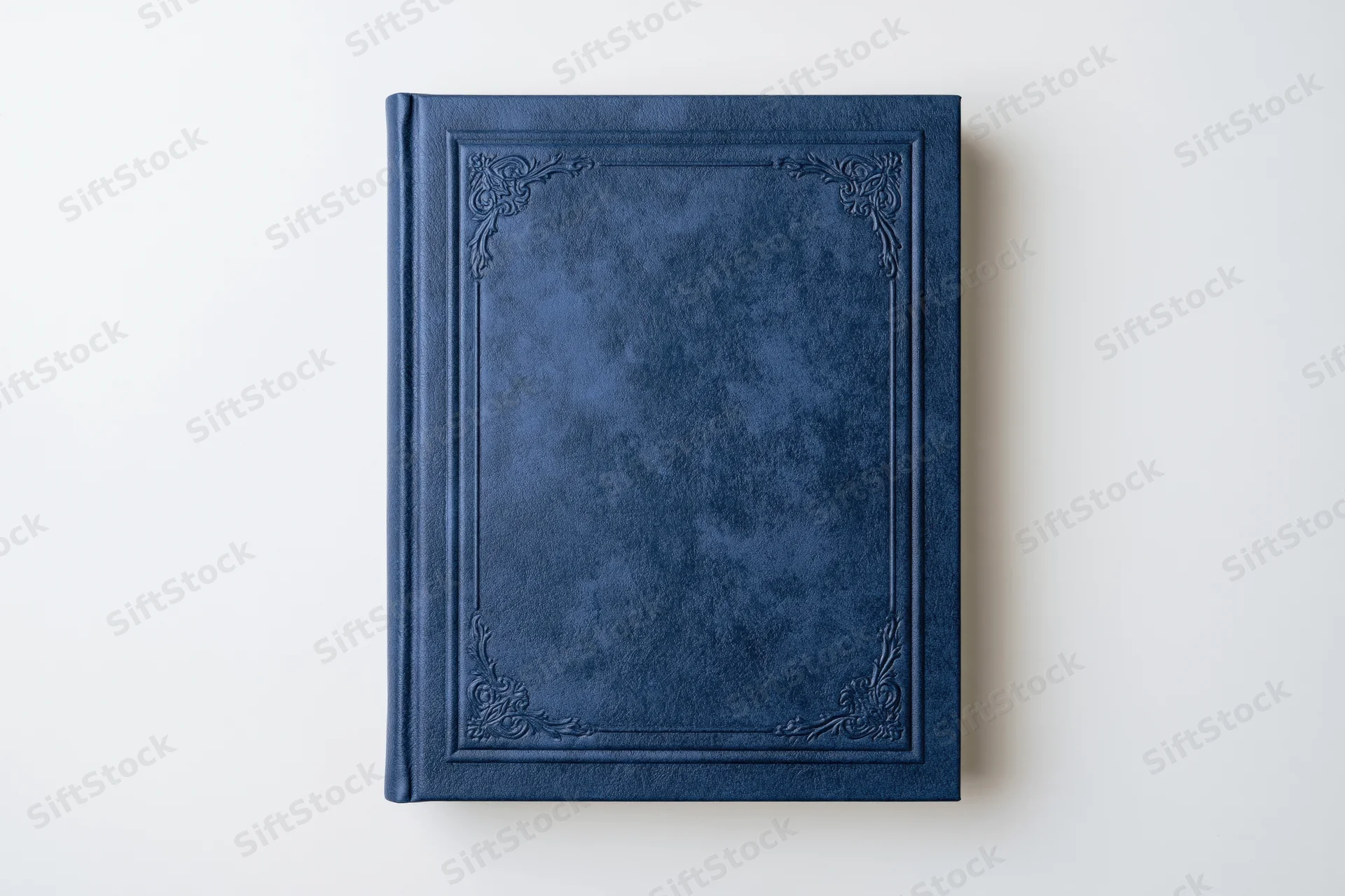 Navy blue leather-bound book with embossed frame lying flat on white surface