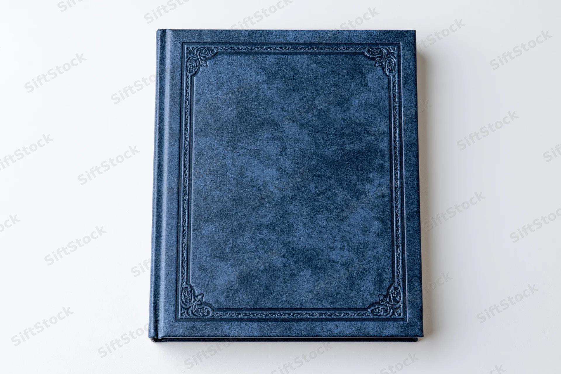 Closed navy blue leather-bound book with embossed decorative border on white background