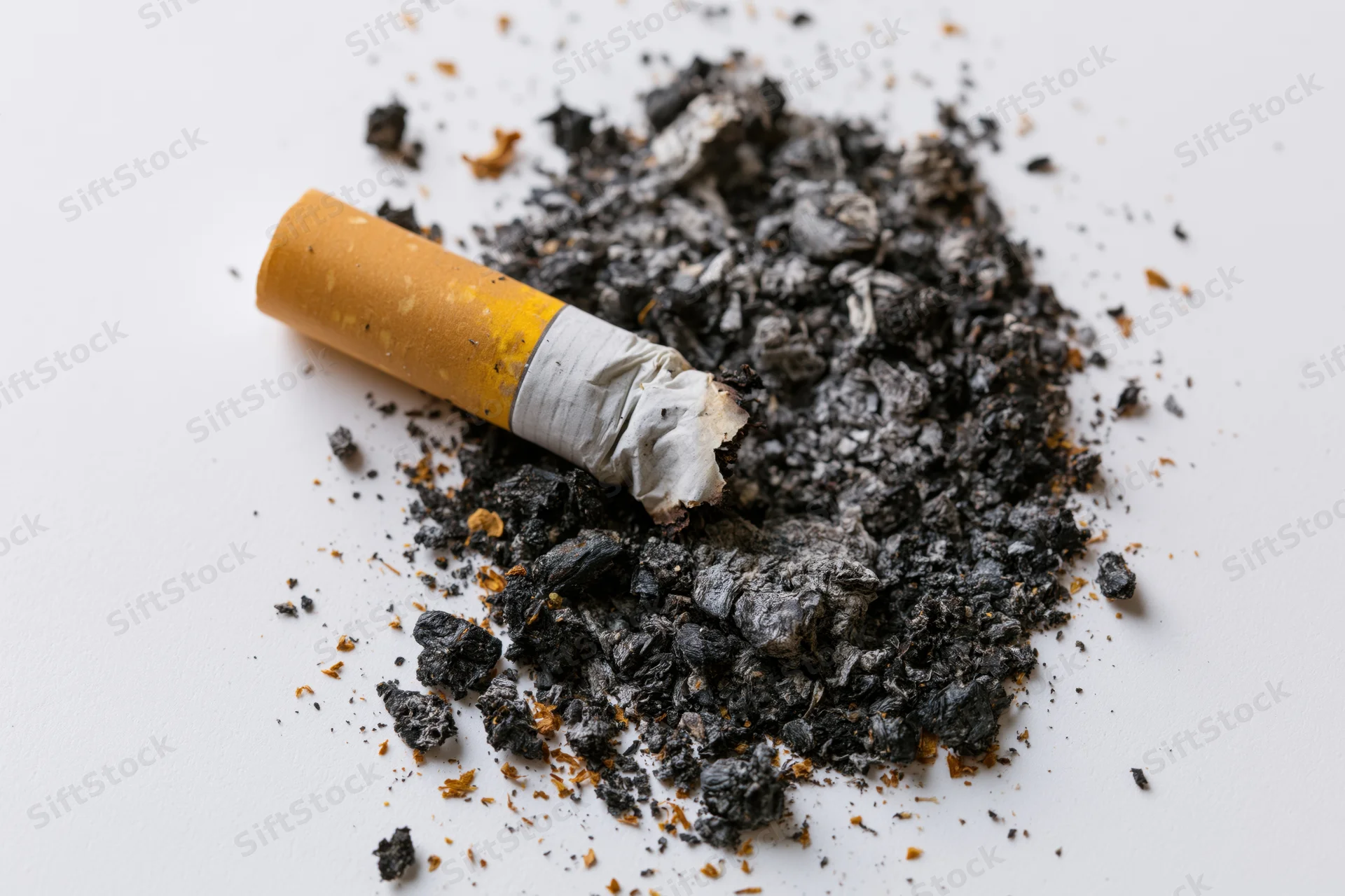 Crushed cigarette butt with ash on white surface