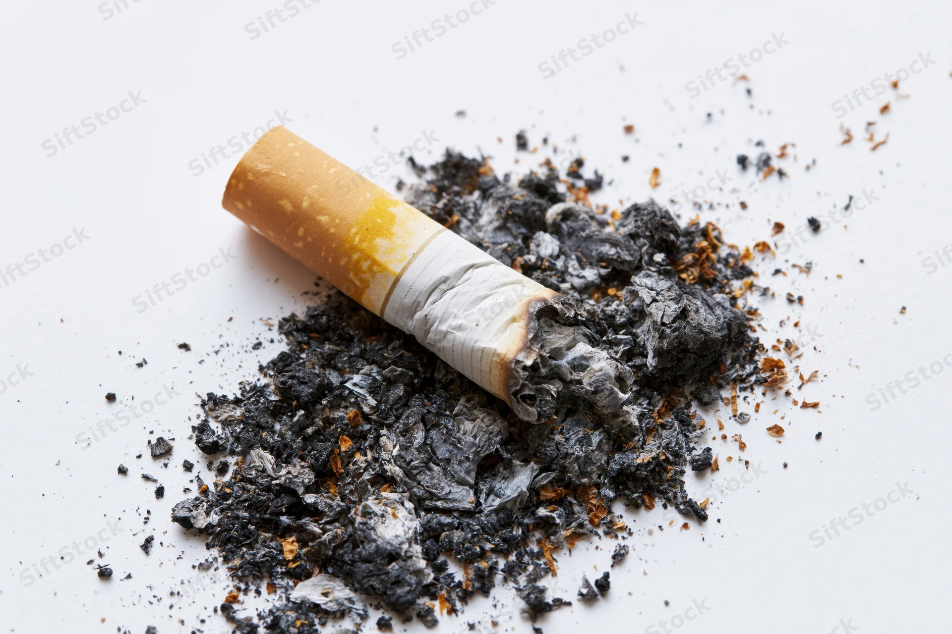 Crushed cigarette butt with ash on white surface