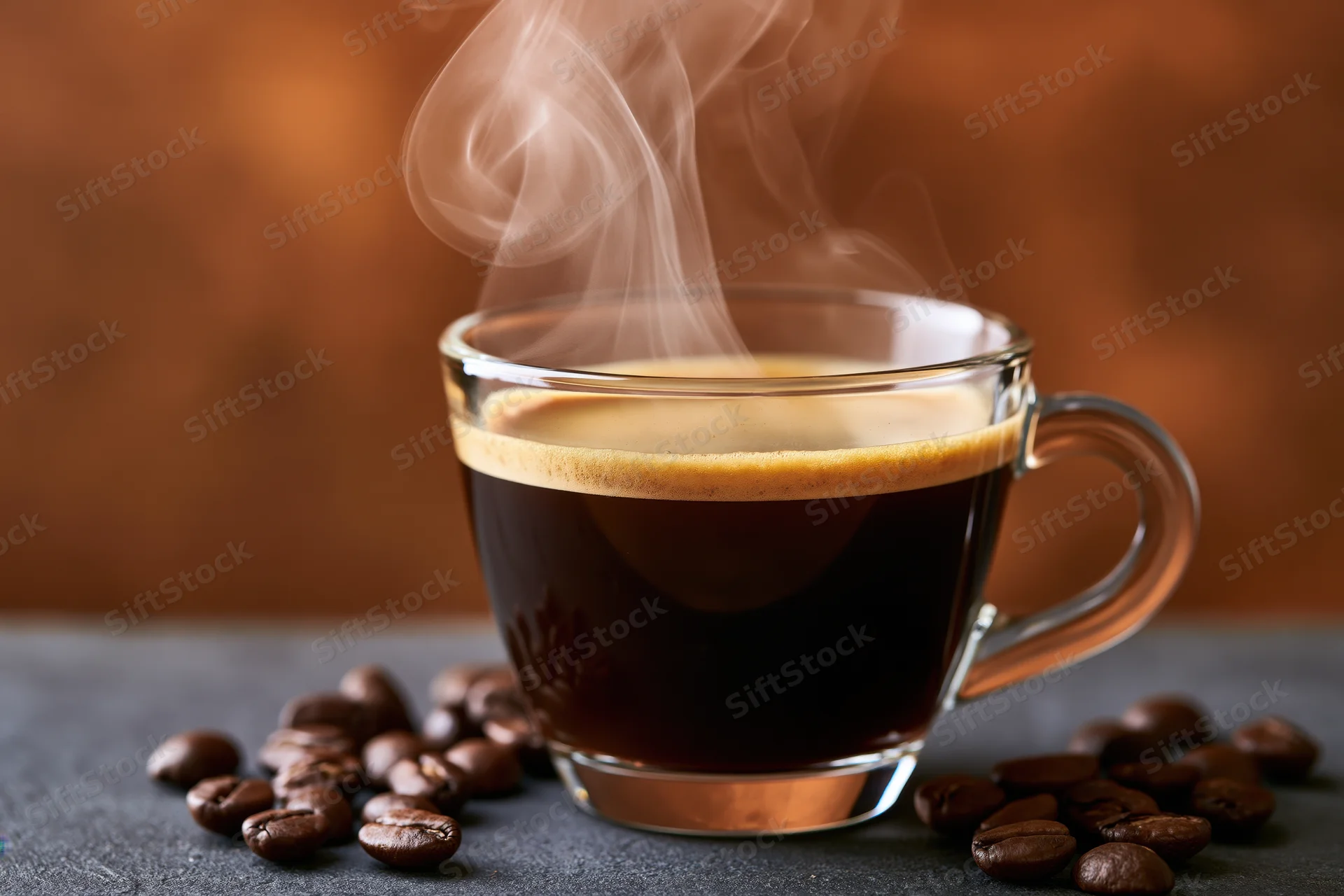 Steaming black coffee in a glass cup surrounded by coffee beans on a dark surface