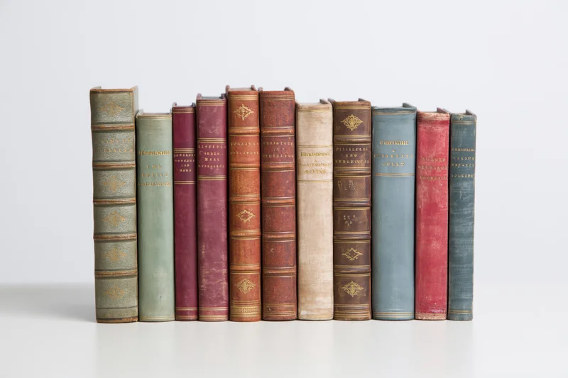 Row of antique hardcover books standing upright on a white surface
