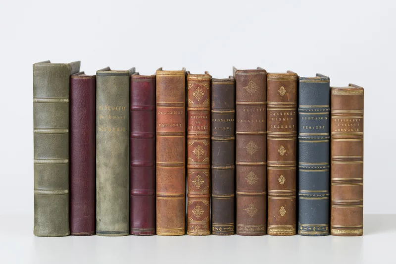 Row of antique hardcover books standing upright on a white surface