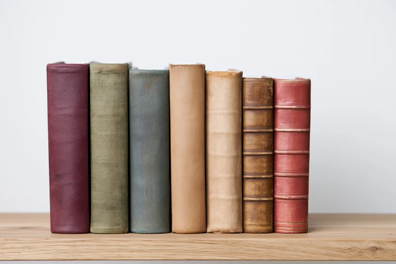 Row of vintage hardcover books standing upright on a wooden table