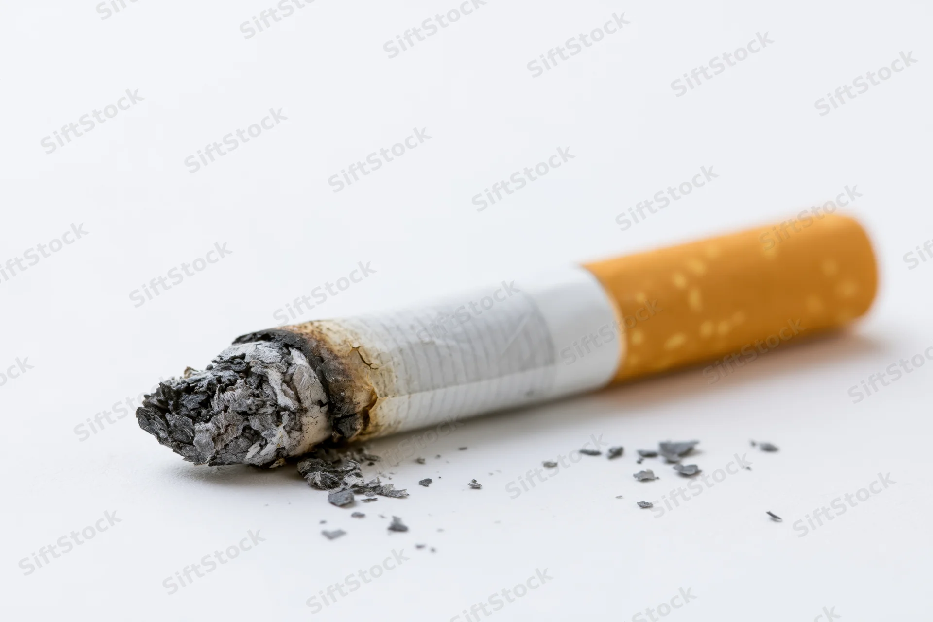 Burnt cigarette butt with ash on white surface