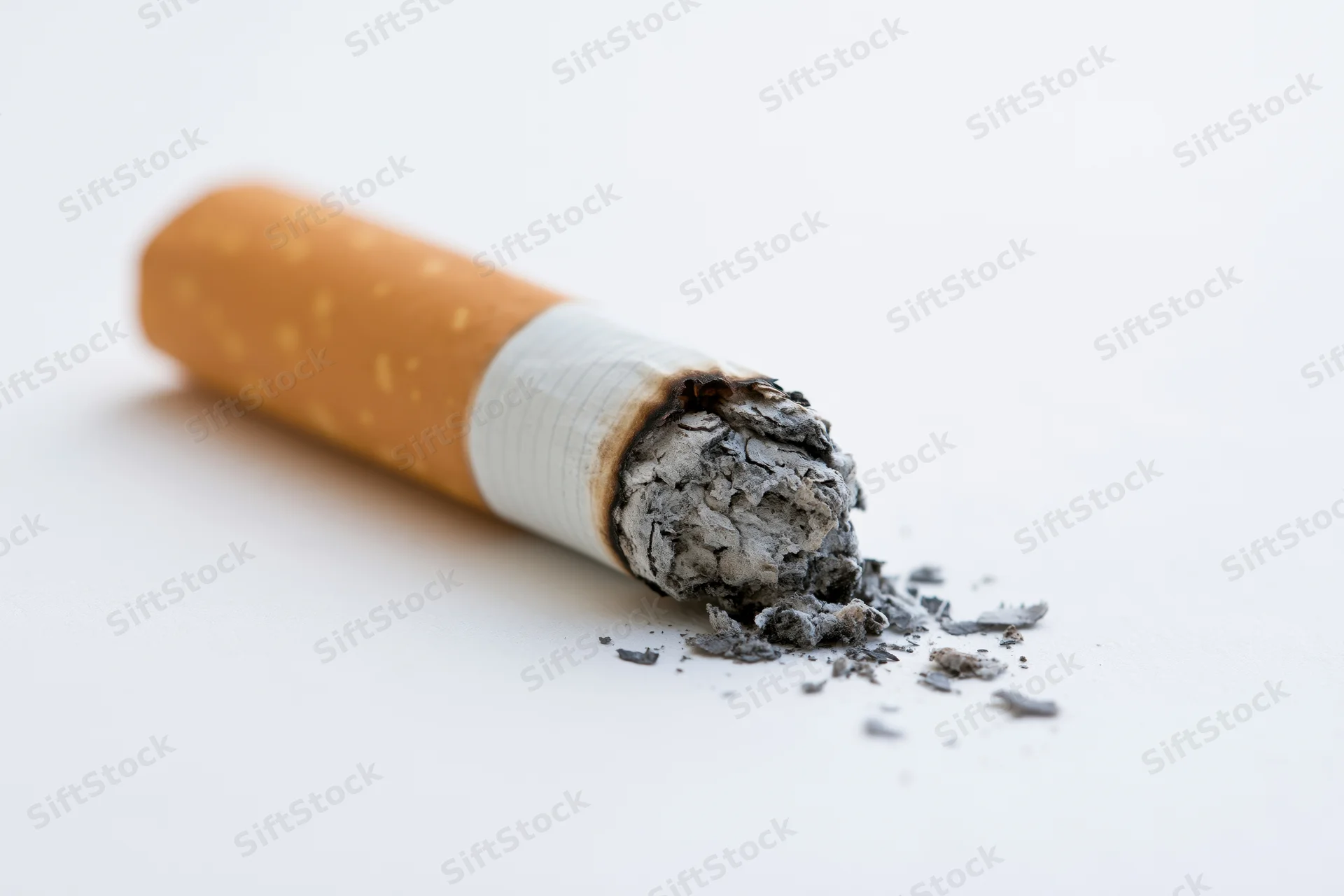 Burnt cigarette butt with ash on white surface