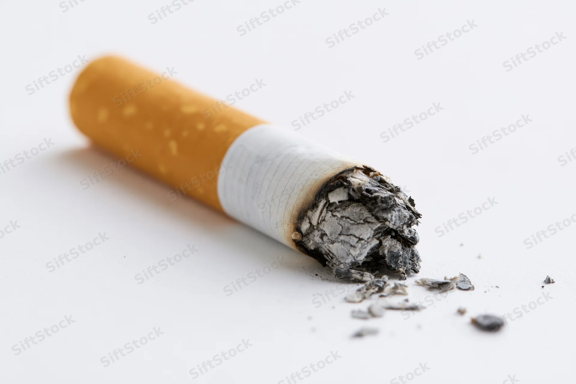 Burnt cigarette butt with ash on white surface
