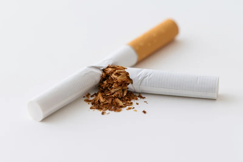 Broken cigarette with spilled tobacco on white surface