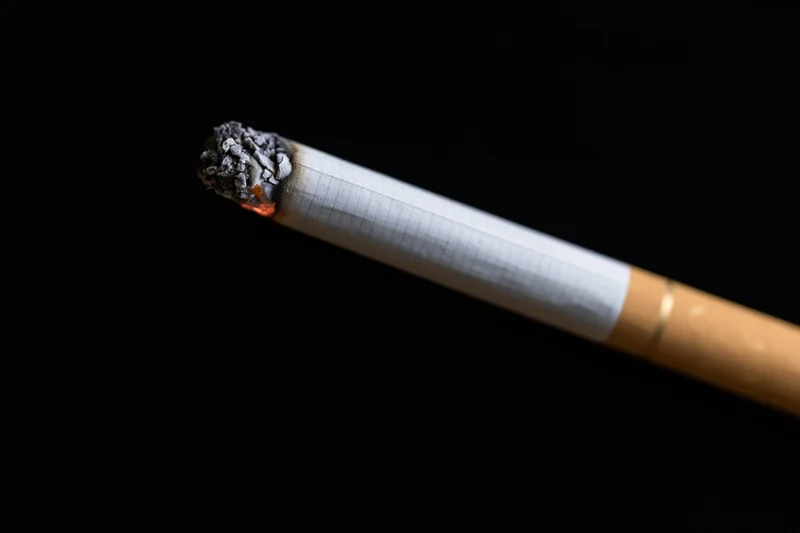 Lit cigarette burning horizontally against black background