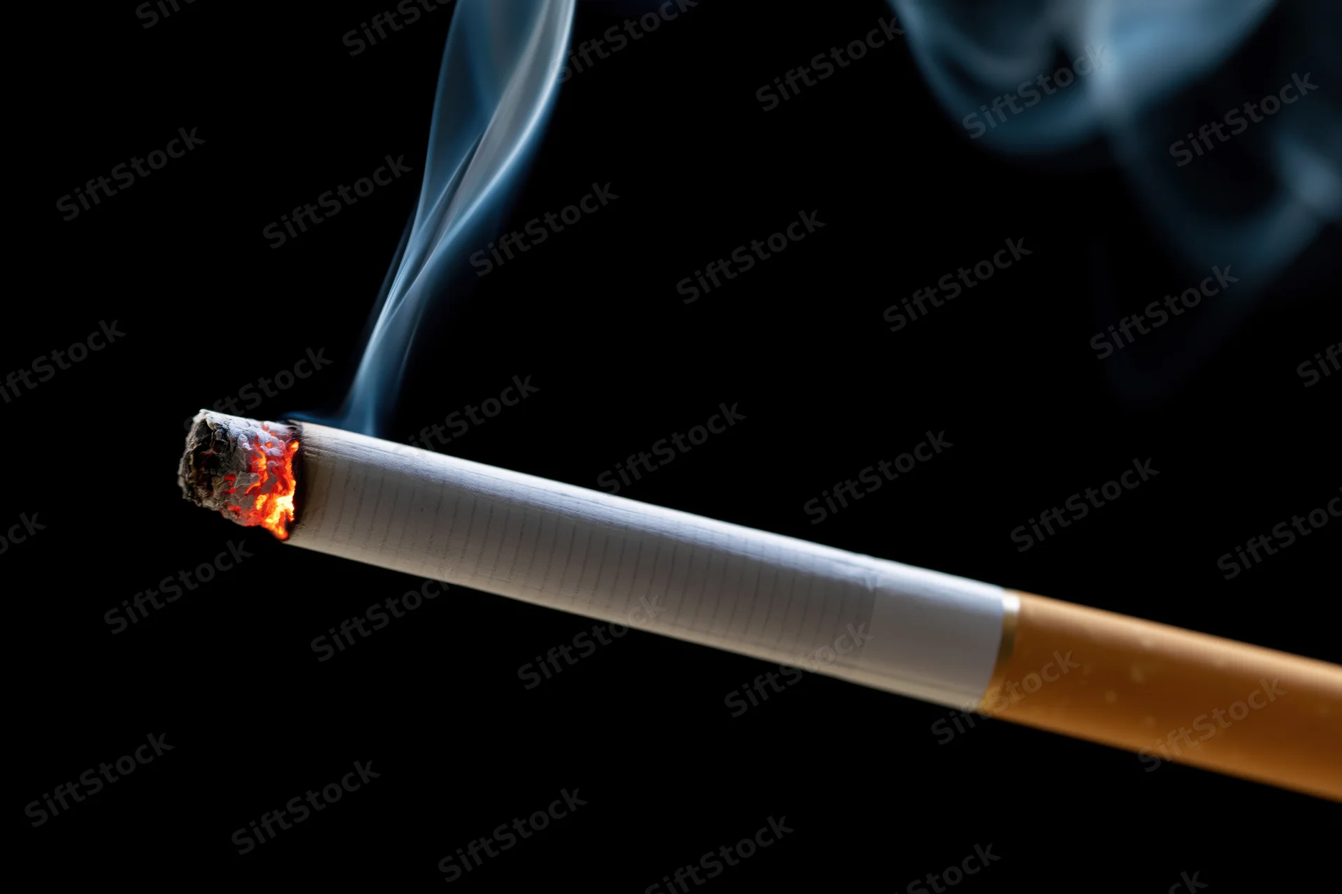 Lit cigarette burning diagonally against black background with rising smoke