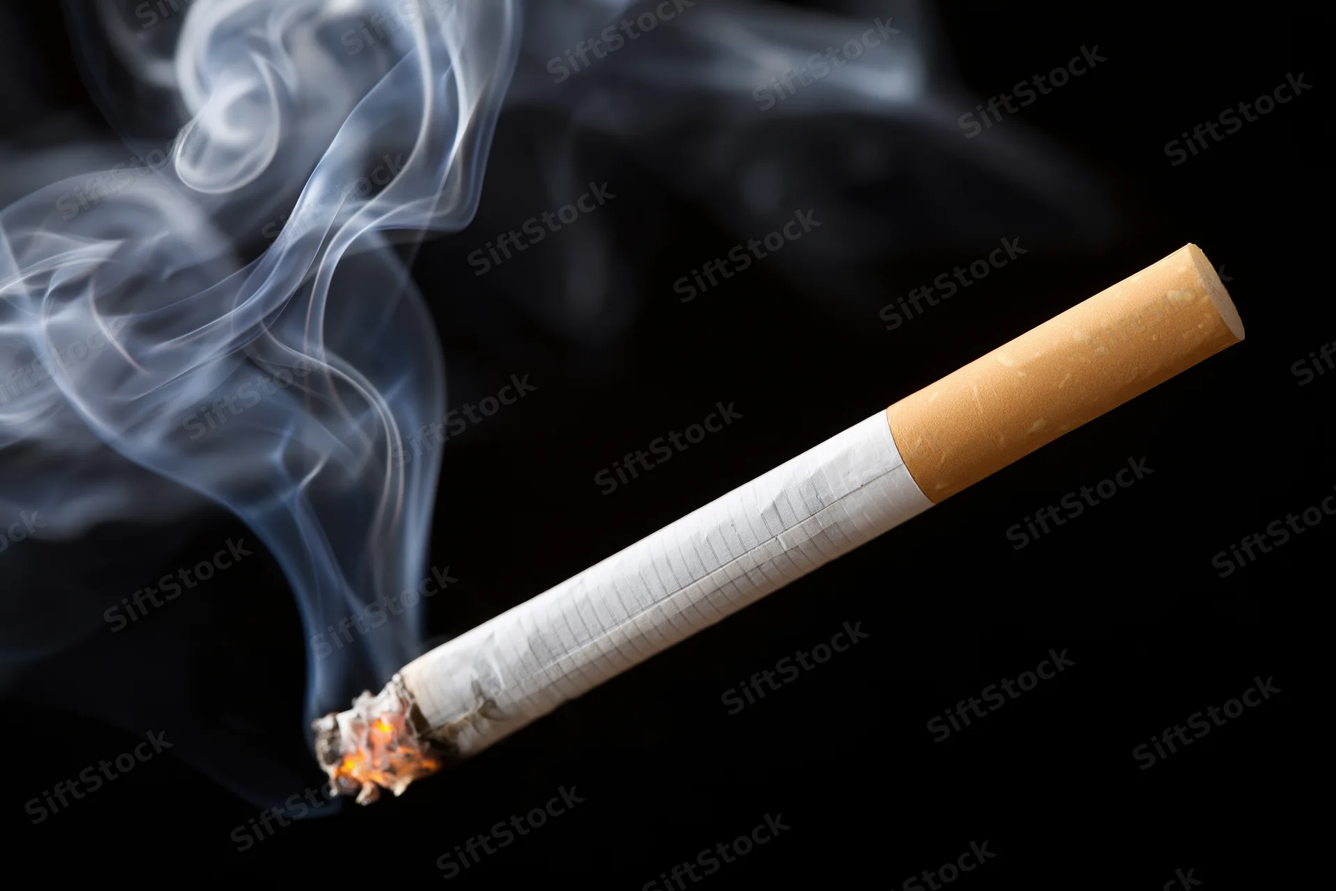 Lit cigarette burning diagonally with curling smoke against black background