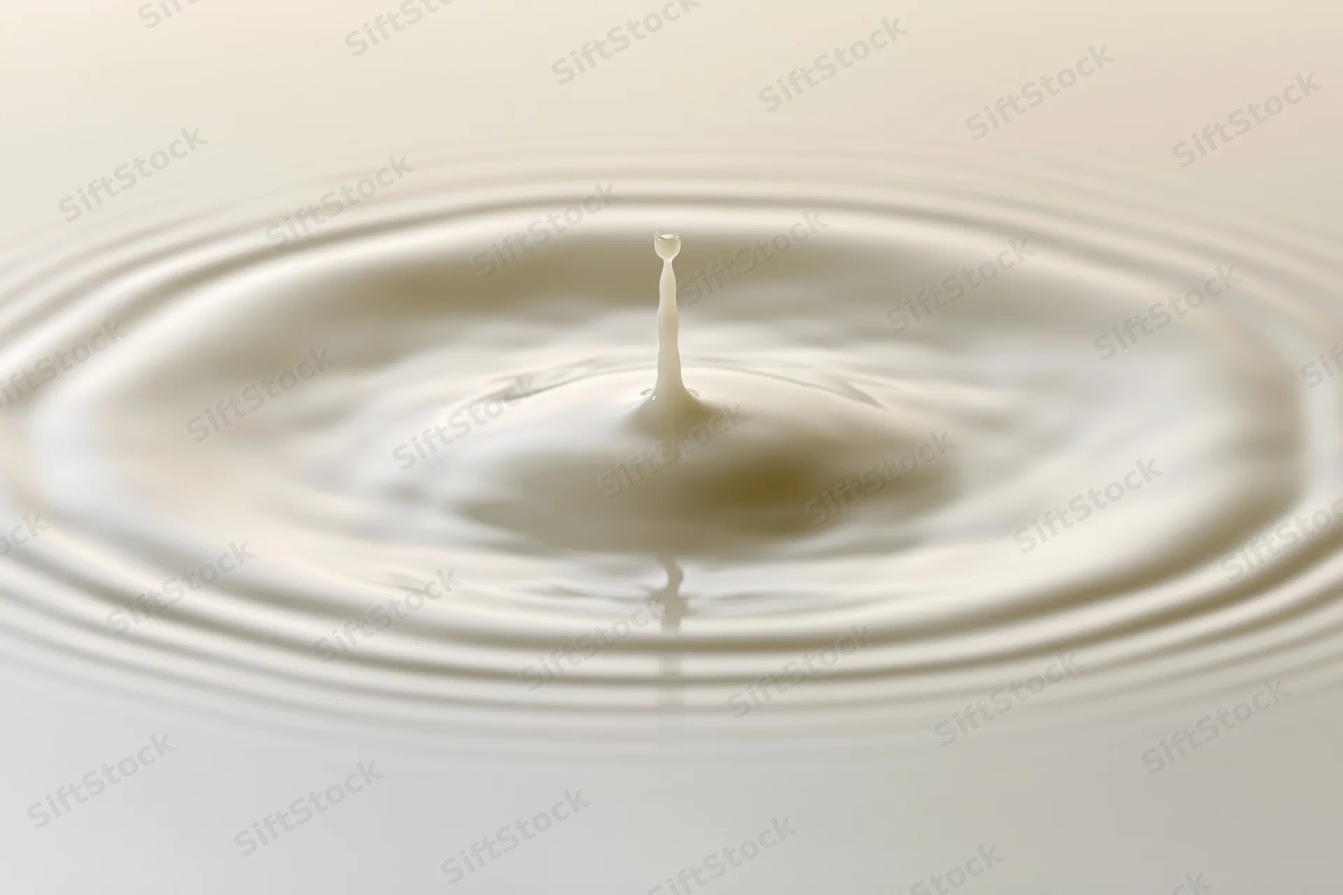 Milk droplet mid-splash rising from smooth surface creating ripples