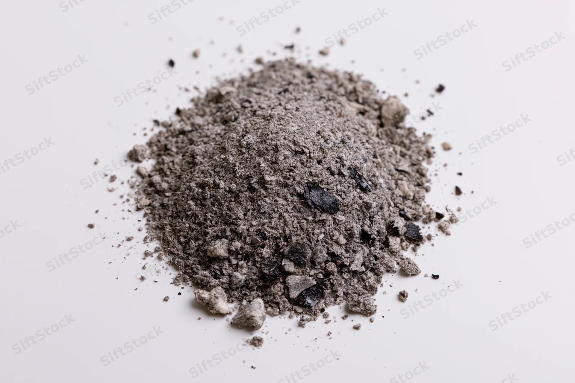 A small pile of grey and black ash debris scattered on a white surface