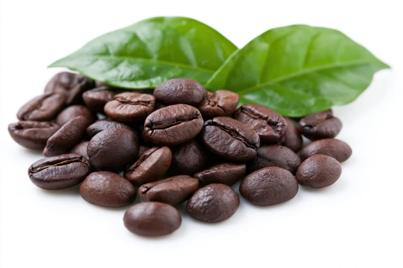 Roasted coffee beans scattered with green leaves on white background