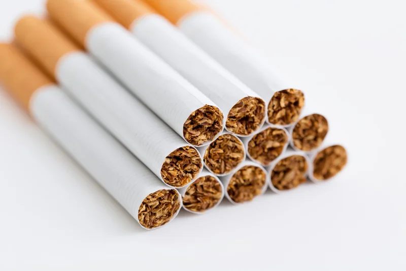 Unlit cigarettes stacked loosely on white background