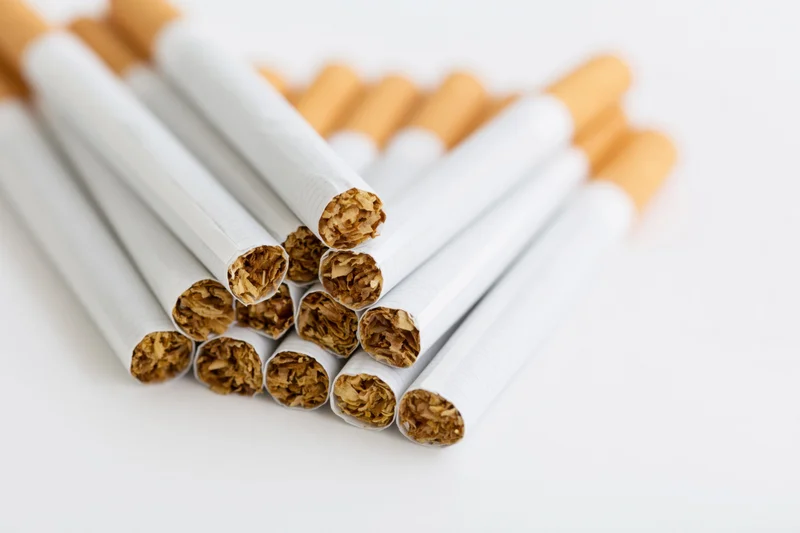 Unlit cigarettes stacked loosely on white surface showing tobacco ends
