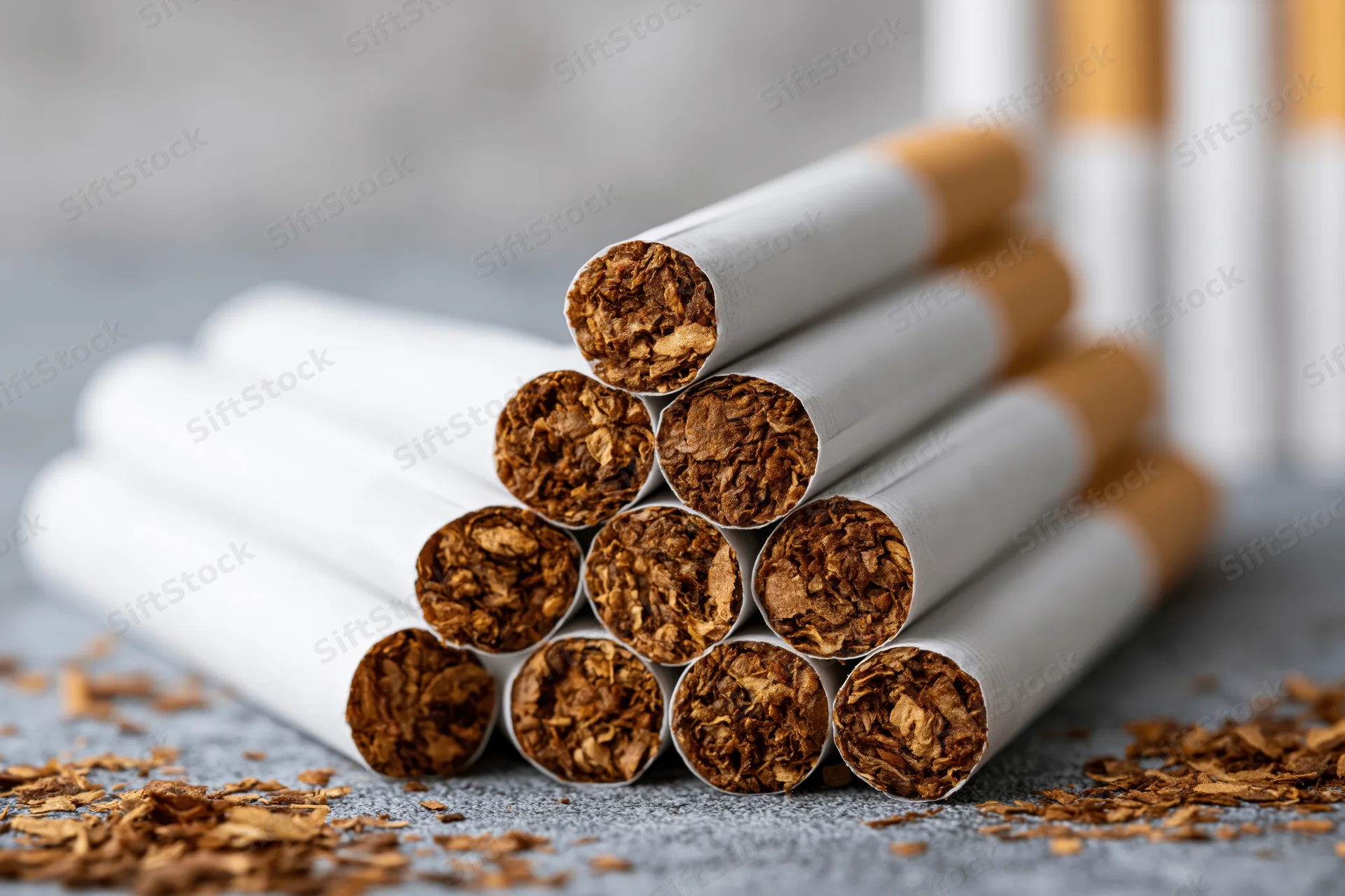 Pyramid stack of unlit cigarettes with visible tobacco fill on textured surface