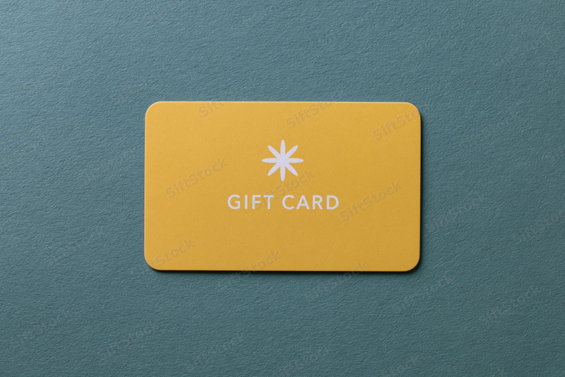 Yellow gift card lying flat on textured teal surface