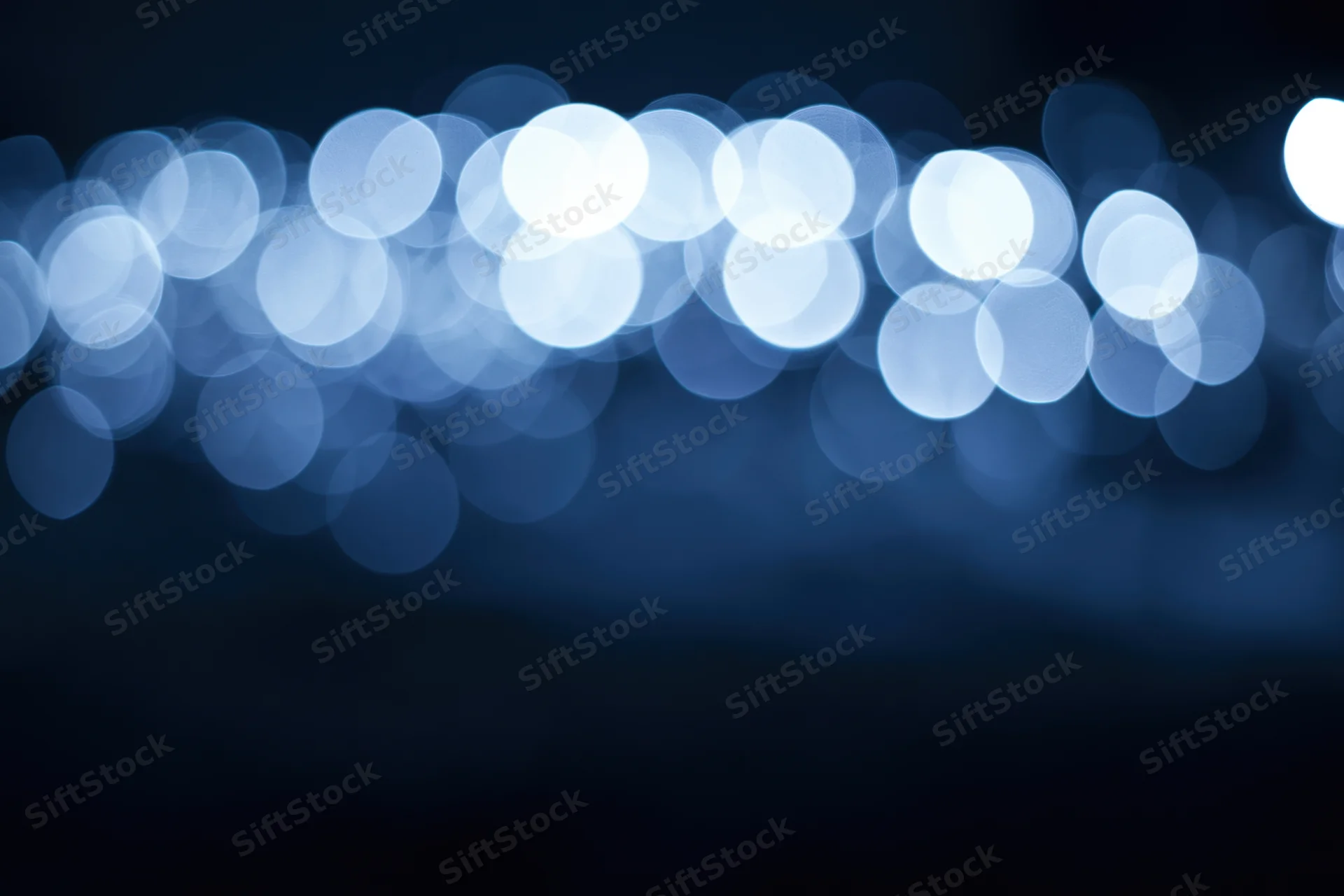 Blurred circular lights in blue tones against dark background