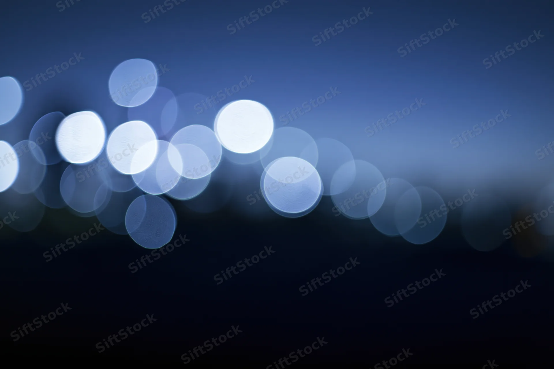 Blurred circular lights in blue gradient background with dark lower half
