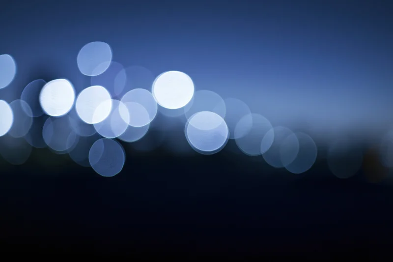 Blurred circular lights in blue gradient background with dark lower half