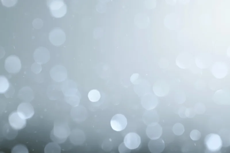 Abstract defocused background with scattered circular bokeh lights in soft white and gray tones
