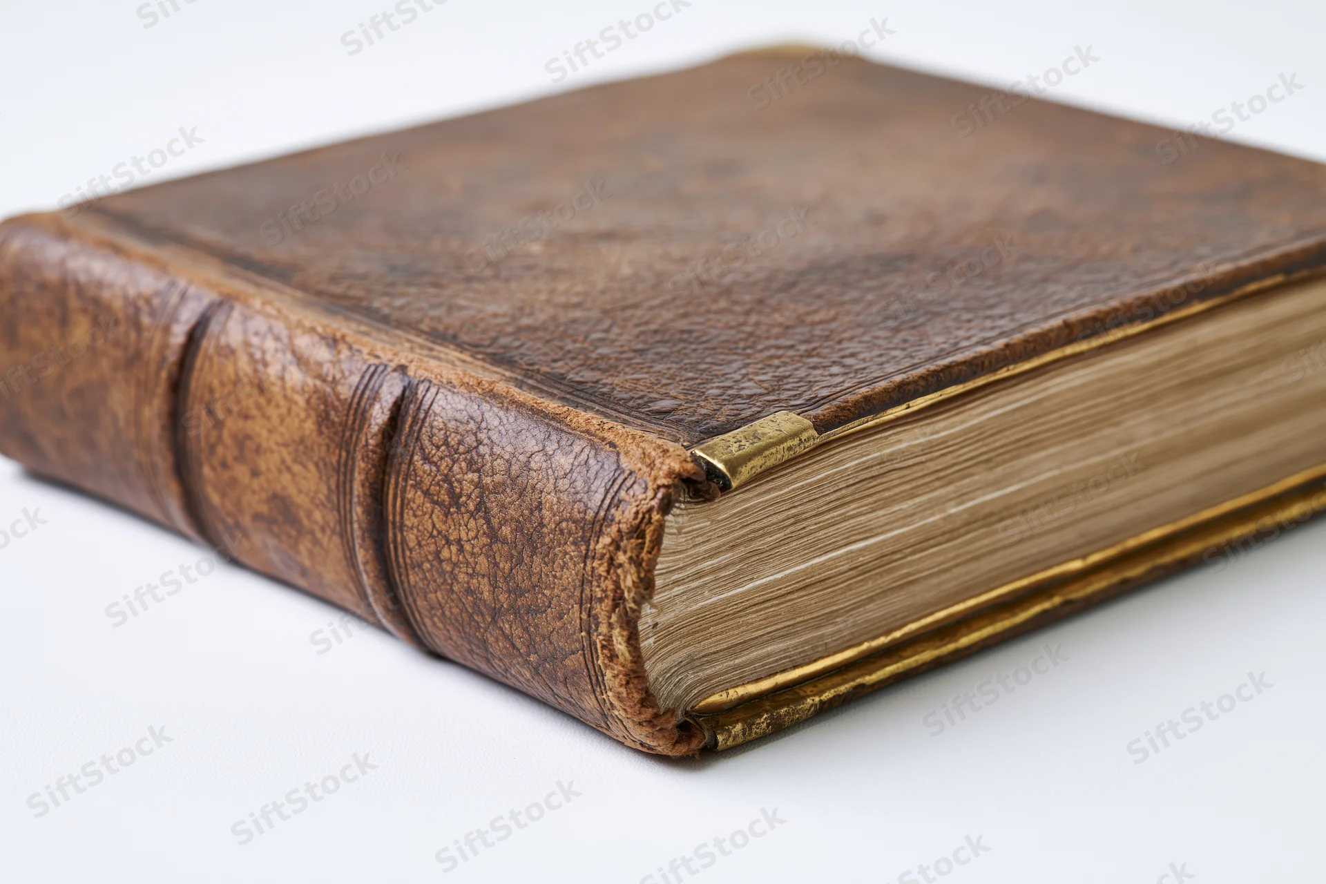 Antique leather-bound book resting at an angle on a white surface