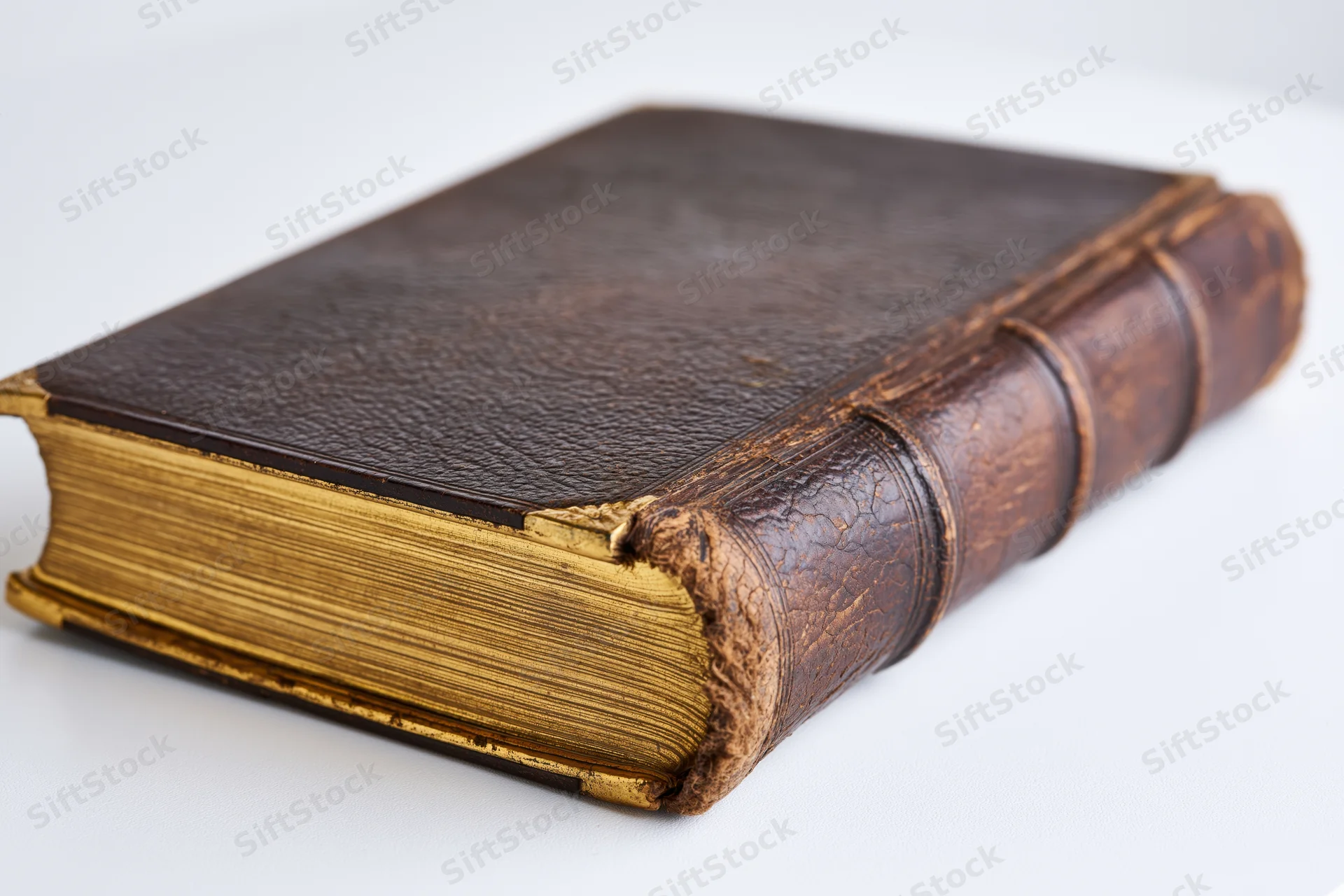 Antique leather-bound book resting at an angle on a white surface