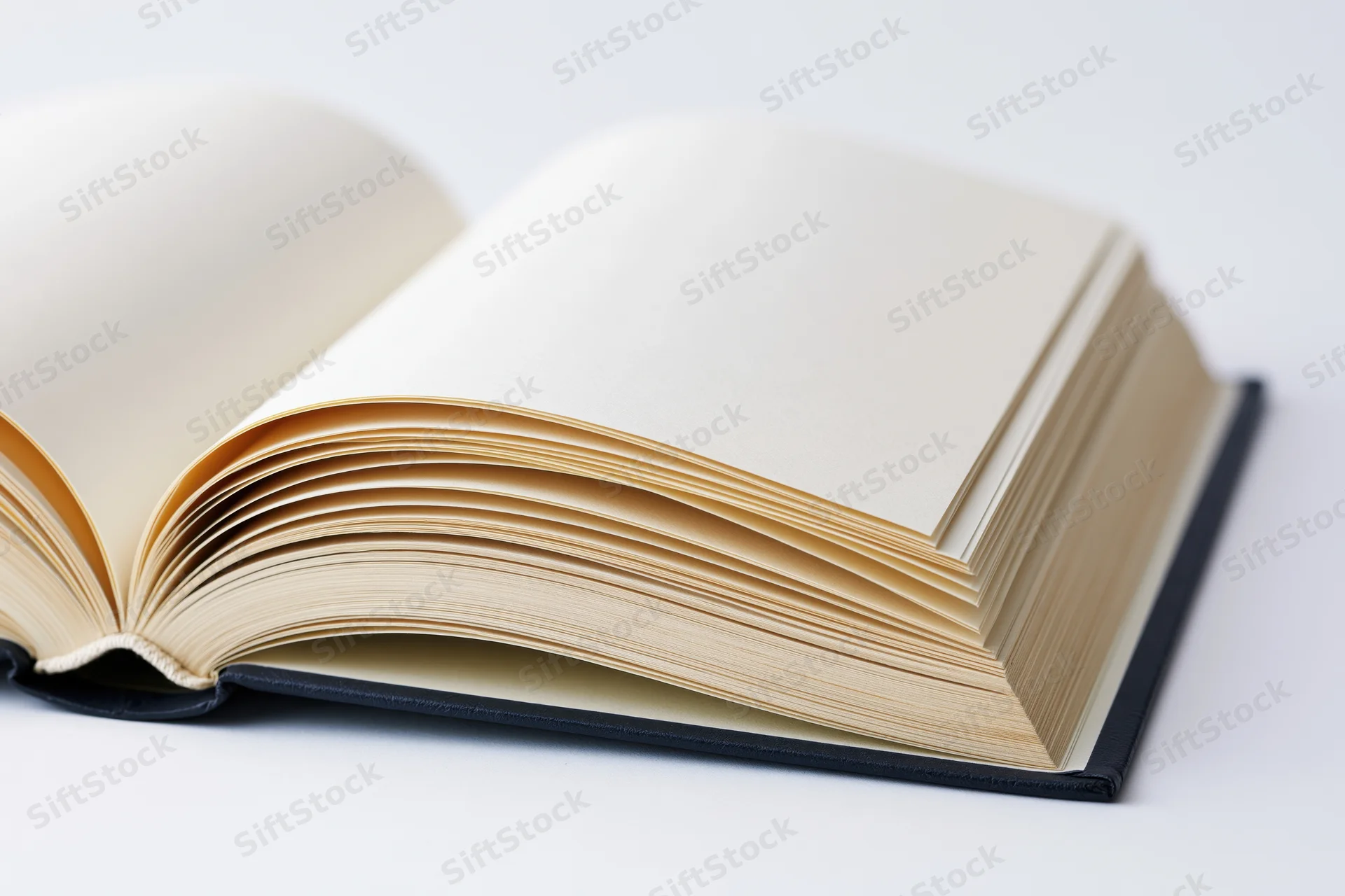Open hardcover book with blank pages spread wide on white surface