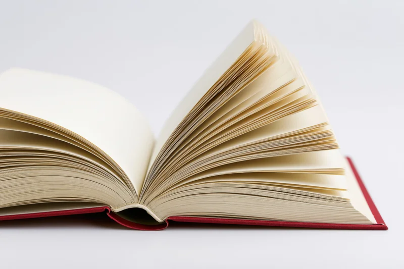 Open hardcover book with pages fanned wide on white background
