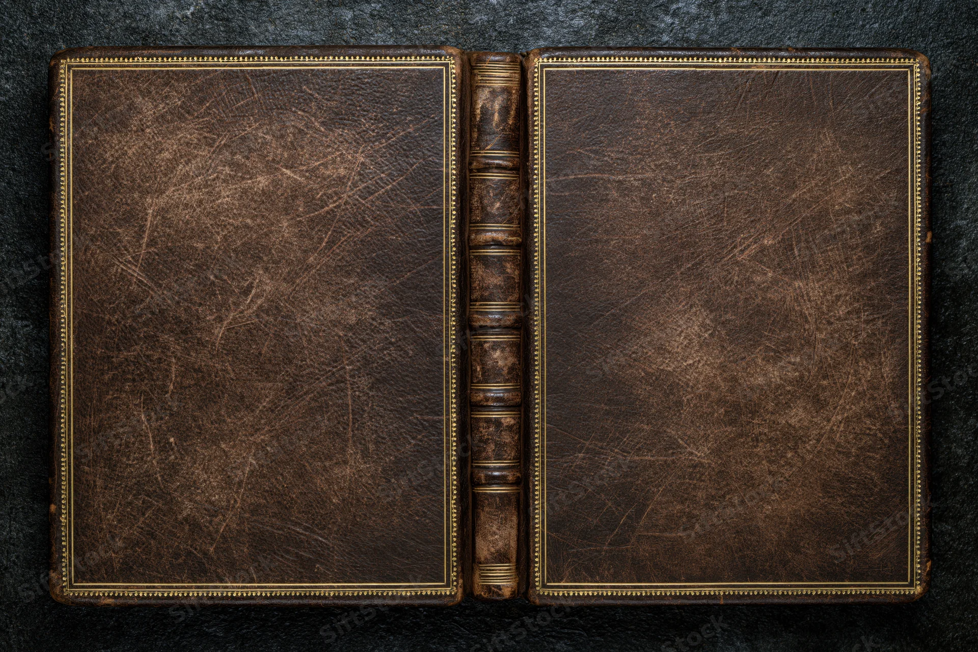 Open antique leather-bound book laid flat showing both covers on dark surface